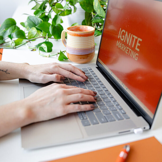 Ignite Marketing Hands typing on a laptop with Ignite Marketing logo